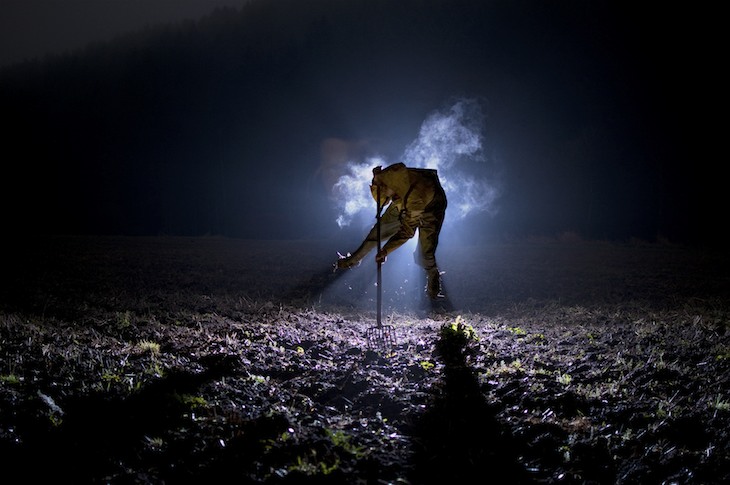 Gestalt mit Lichtquelle auf einem nächtlichen Feld, Licht bricht durch Nebel
